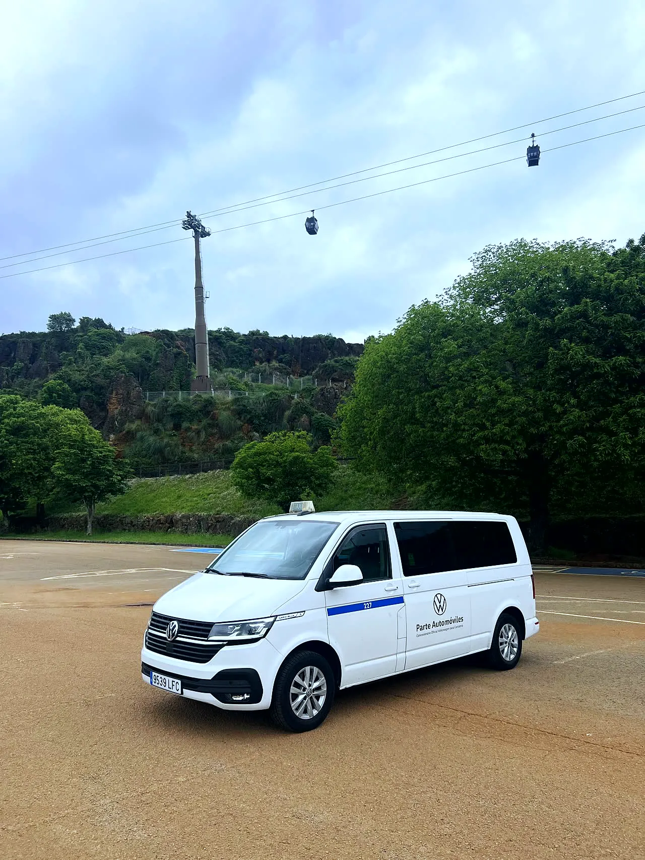 White 8-seater van parked at Cabárceno Nature Park with the cable car in the background