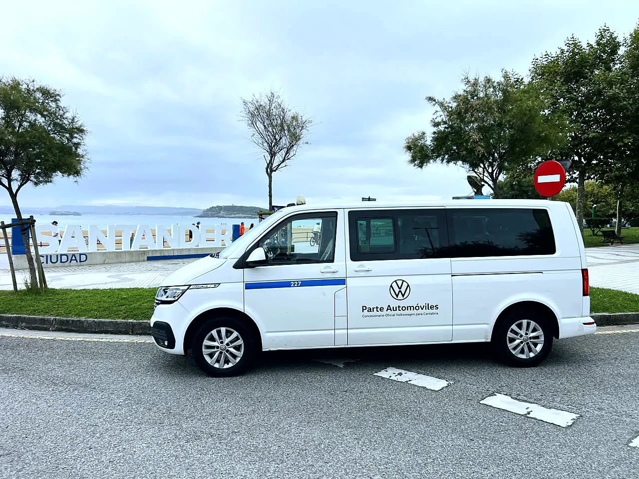White 8-seater van next to the Santander letters opposite the beach